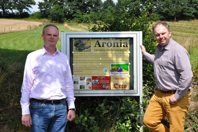arsten und Christian Ilsemann vor dem Schaukasten an einem ihrer Aronia-Felder.