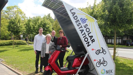 Gruppenfoto: Vier Personen hinter einer Solarladestation.