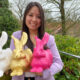 junge Frau hält drei verschiedenfarbige Hasen aus Plastik.